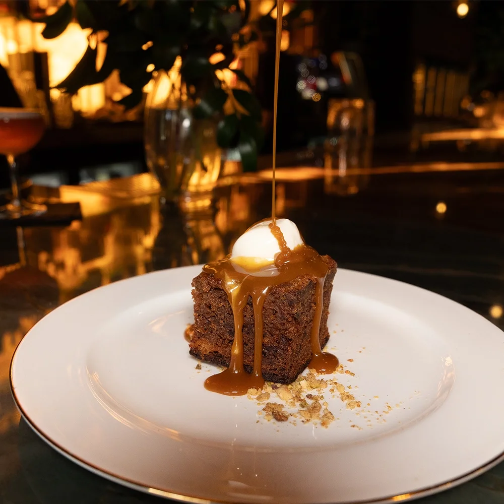 Warm date cake dessert with caramel sauce and vanilla gelato