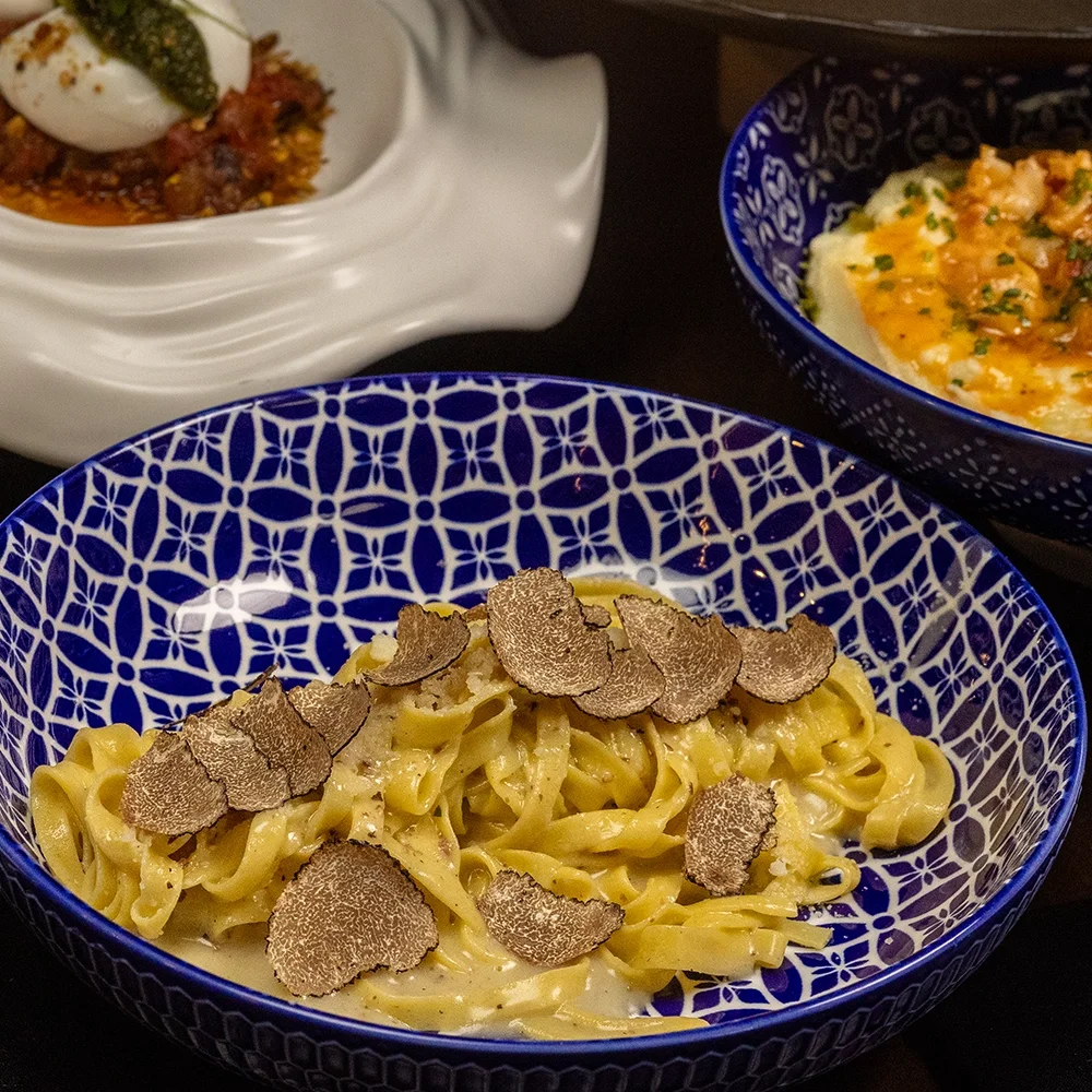Tagliatelle with shaved black truffle served in a blue patterned bowl