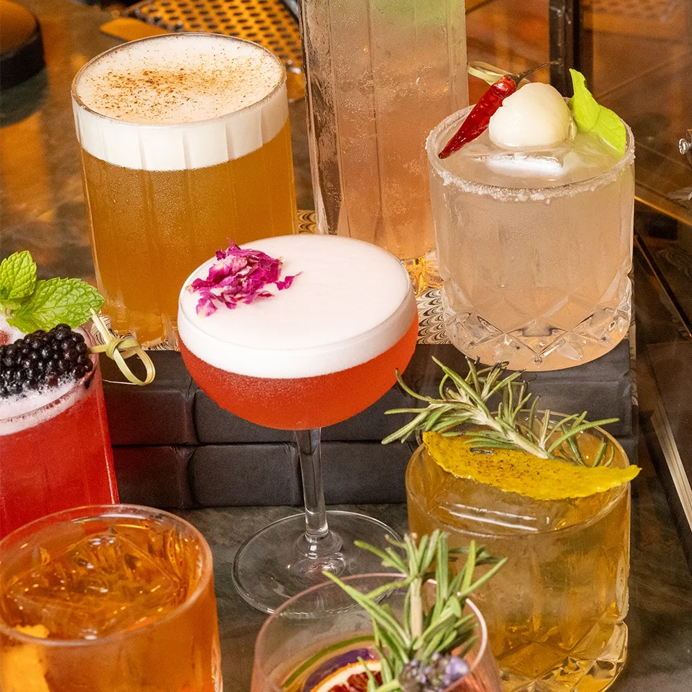 Three craft cocktails garnished with edible flowers on the bar at WeVINO