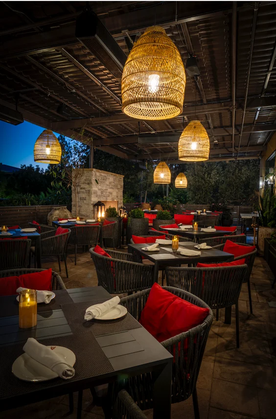 WeVINO outdoor terrace at dusk with hanging lanterns and red dining chairs