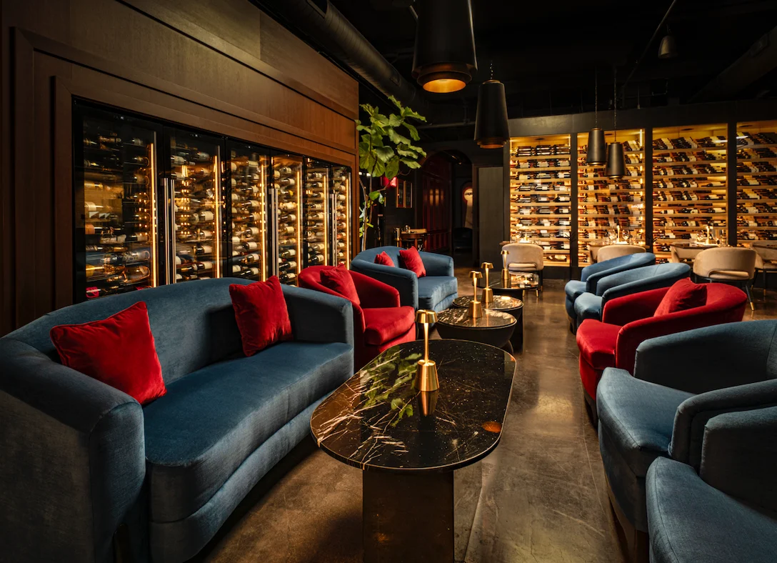 Teal velvet sofa at WeVINO set against tall wine cellar shelving