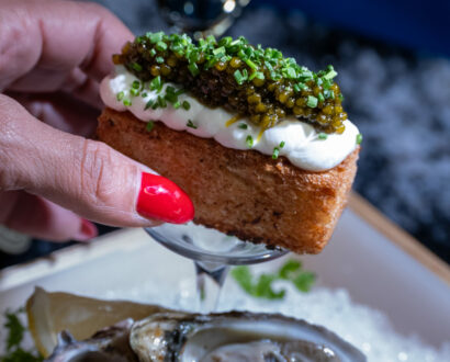 Crostini topped with whipped ricotta and fresh herbs held in hand