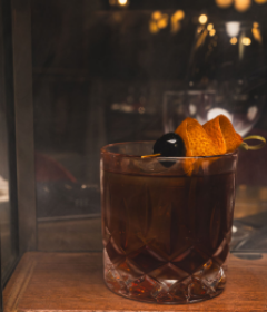 Old fashioned cocktail served over ice with an orange twist