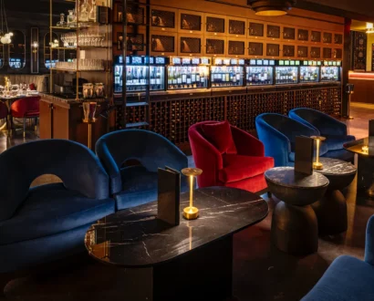 Lounge at WeVINO with blue velvet seating beside the backlit Enomatic wine wall
